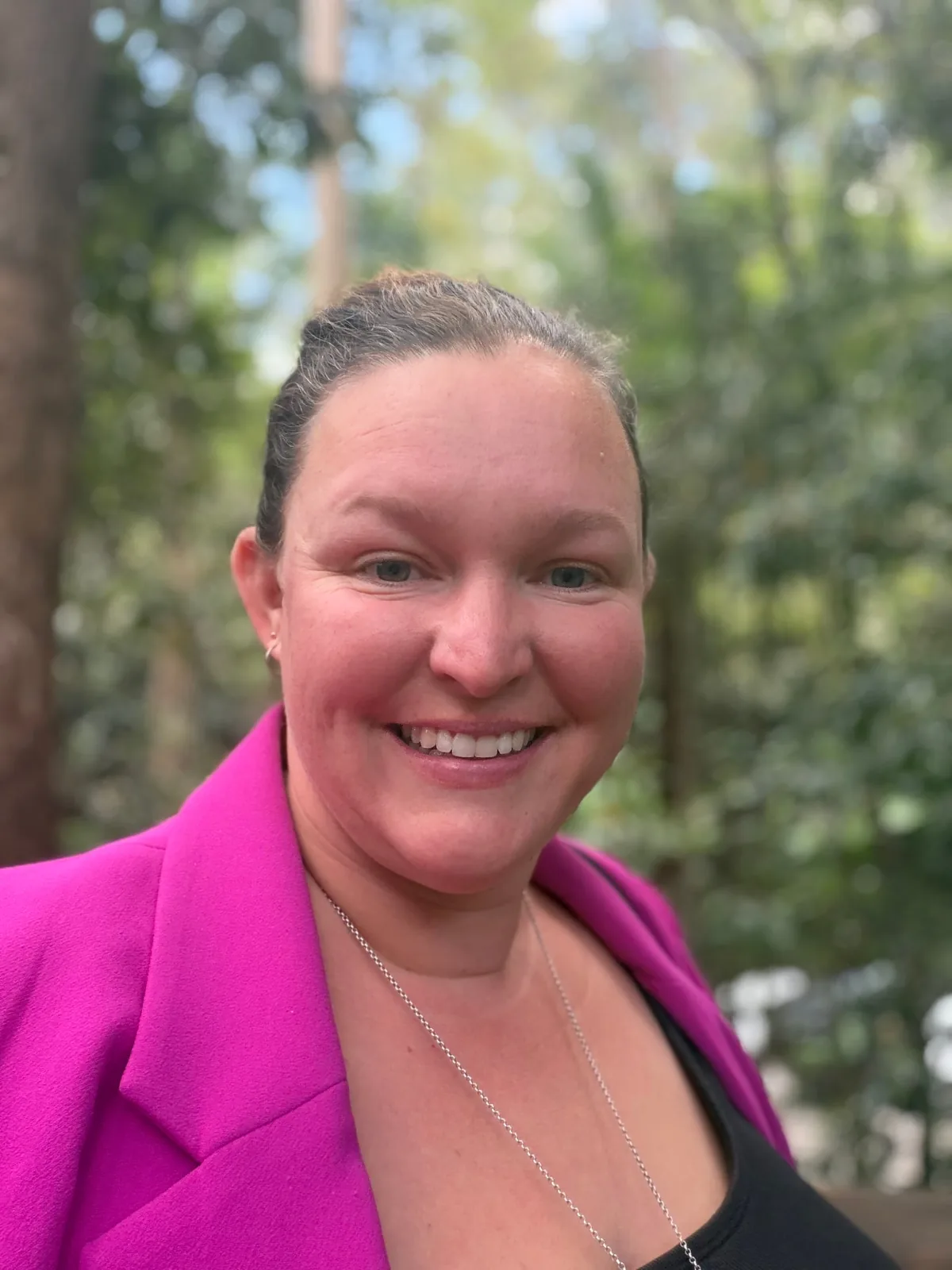 Rachel Smith, founder of The Educators Well, smiling outdoors in a magenta blazer