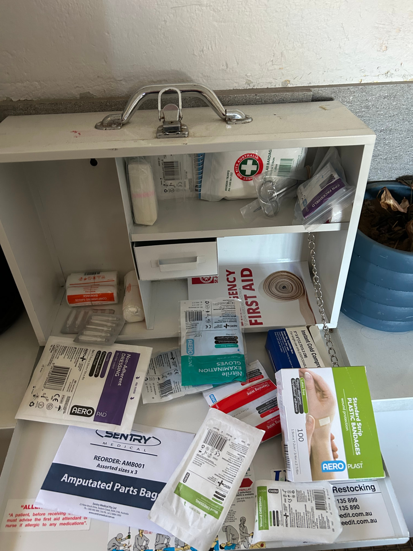 An open first aid kit with bandages, gloves, dressings and plastic strips spread out to explore